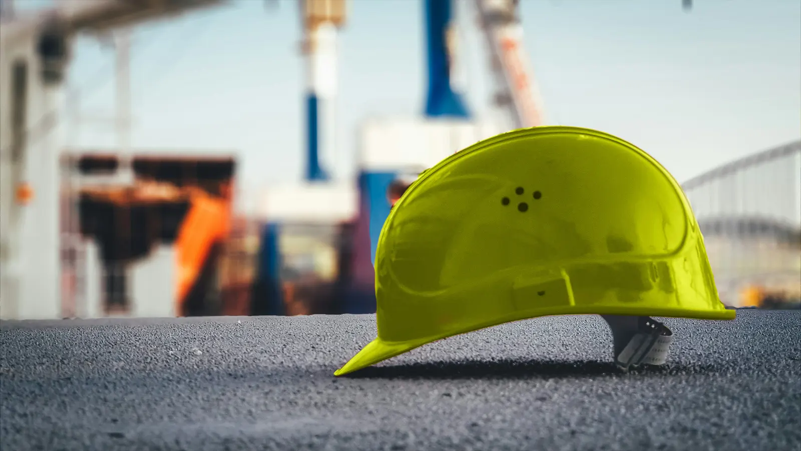 Casque de chantier posé sur le sol devant une structure industrielle
